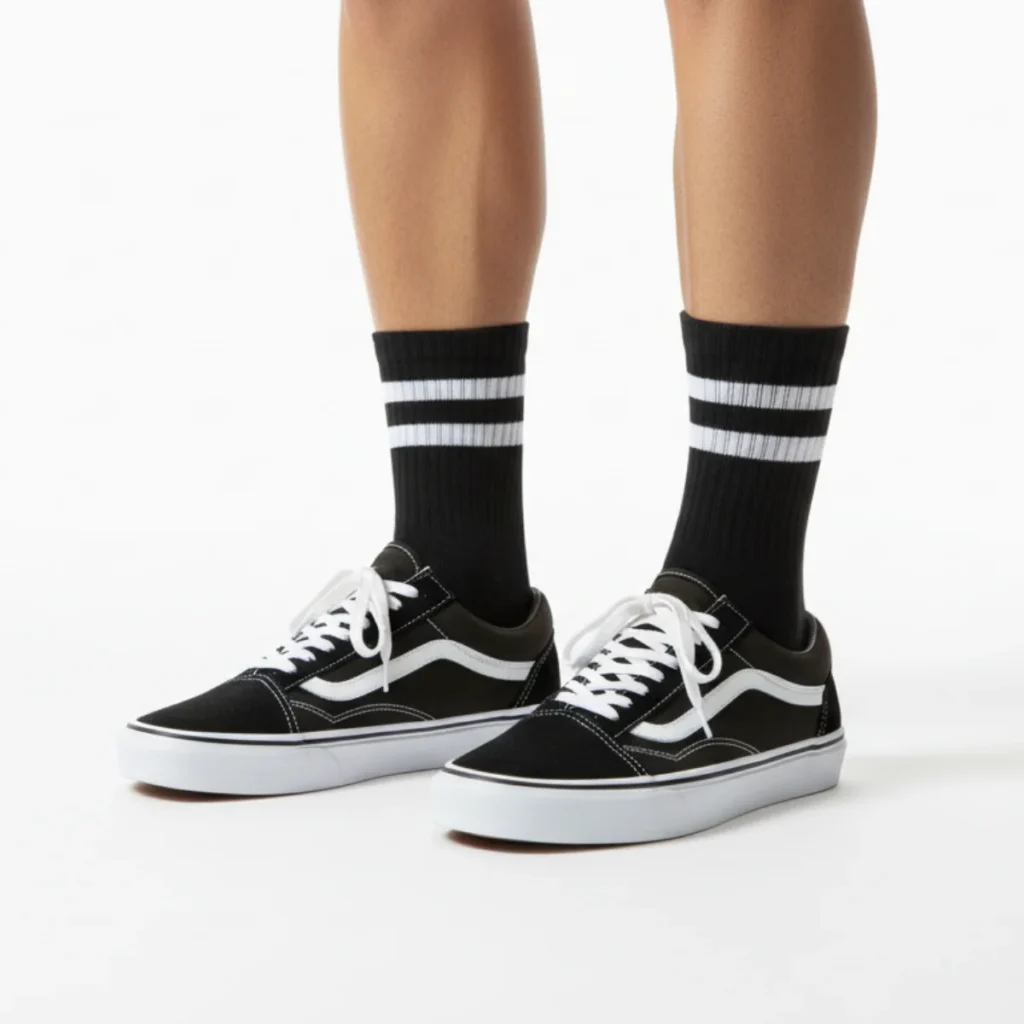 Siyah üzerine beyaz çizgili kolej tarzı spor çorap ve siyah Vans ayakkabı kombin görünümü.