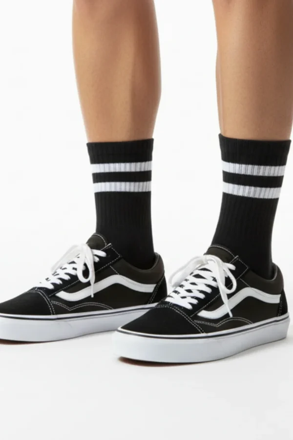 Siyah üzerine beyaz çizgili kolej tarzı spor çorap ve siyah Vans ayakkabı kombin görünümü.