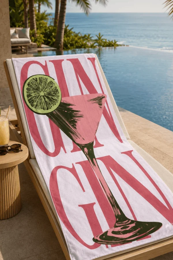 Demi Bravo GIN Coctail plaj havlusu, deniz manzaralı sonsuzluk havuzu yanında şezlong üzerine serilmiş.